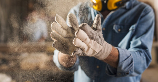 An employee claps dust out of their white work gloves, wearing a yellow headset around their neck and a denim button up.