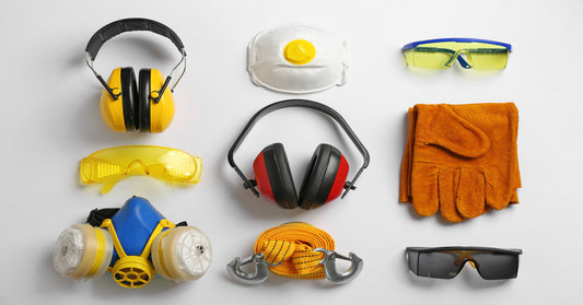 A white table with an arrangement of personal protective equipment, including gloves, headphones, glasses, and masks.