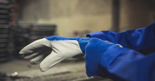 A close-up of a person in a blue safety jacket with long sleeves and matching, blue and white cut-resistant gloves.