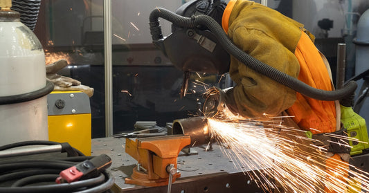 A welder in the shop wears flame-resistant clothing as they're close to the sparks flying off the welding equipment.