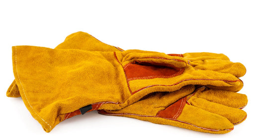A pair of brown leather palm work gloves sit on a white surface. The gloves show signs of wear but are relatively clean.